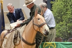 David Ryder, U.S. Mint director, and Charles Mark, Salmon-Challis National Forest superviser, from left, pour newly minted Frank Church River of No Return Wilderness quarters into Buck’s saddlebags as the new coin is released on Wednesday, Nov. 6, 2019, during a ceremony at Salmon Junior-Senior High School in Salmon, Idaho. The coin is the 50th in the U.S. Mint’s America the Beautiful series of quarters.  (© 2019 Cindi Christie/Cyanpixel)