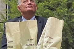 David Ryder, director of the U.S Mint, is seated behind currency bags as the Frank Church River of No Return Wilderness quarter is released on Wednesday, Nov. 6, 2019, during a ceremony at Salmon Junior-Senior High School in Salmon, Idaho. The coin is the 50th in the U.S. Mint’s America the Beautiful series of quarters. (© 2019 Cindi Christie/Cyanpixel)